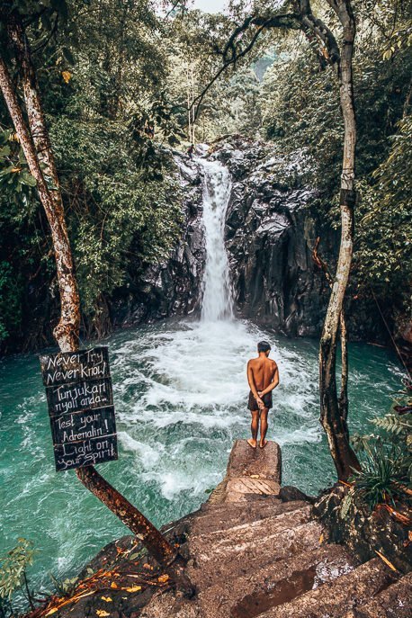 A local boy observes the water from the jumping platform at Kroya Waterfall, Bali Gallery