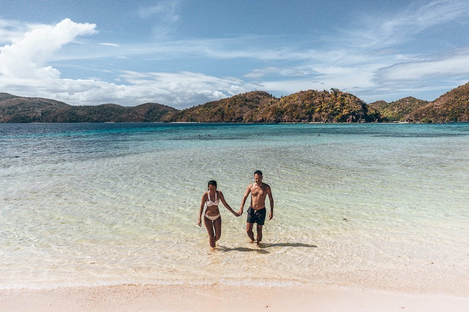 A couple wade through the shallow waters on Malcupuya Island, Coron