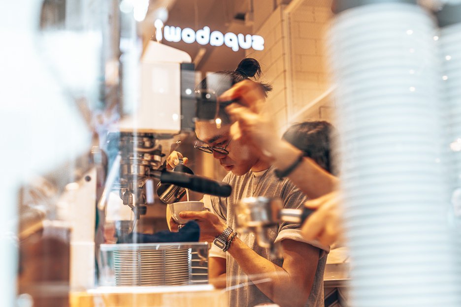 Watching a barista through the glass window meticulously prepare a cup of coffee inside NOC Coffee - Graham Street, Hong Kong