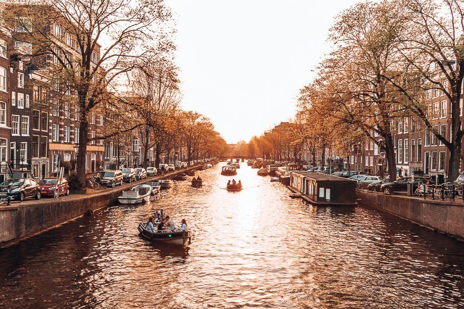 Boats cruise along the canals during sunset in Amsterdam, The Netherlands