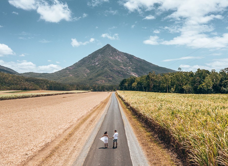 A couple walk along Behana Gorge Road with Walsh's Pyramid in the background, Queensland