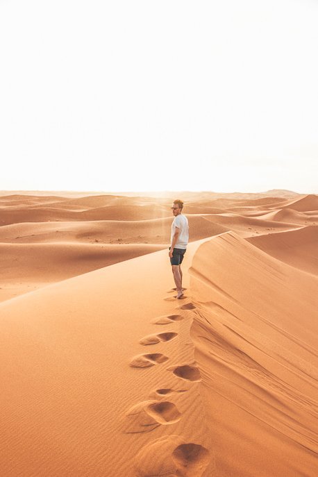 A man leaves footprints along a dune in the Sahara Desert, Morocco