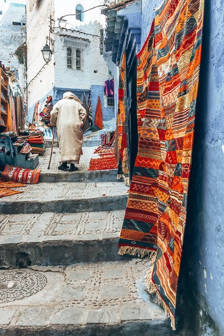 A berber man shuffles up some stairs in the city of Chefchaouen, Morocco
