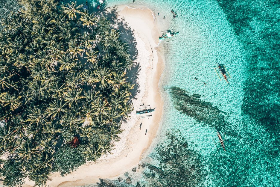 Guyam Island from above. Palm trees, beach and water