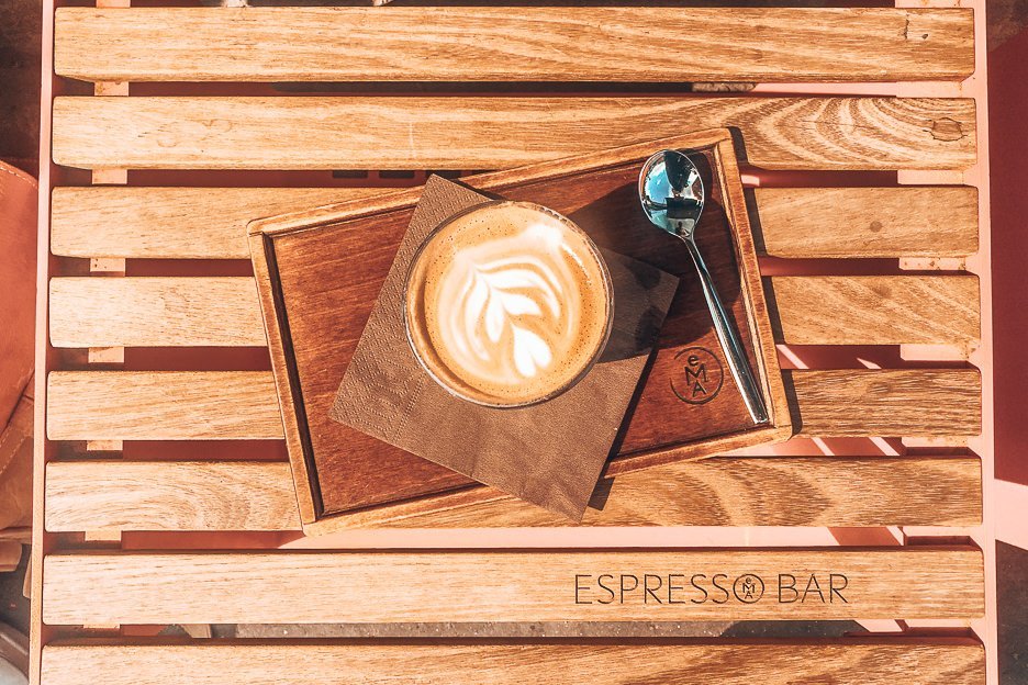 A latte on a wooden seat at EMA Espresso Bar, Prague,